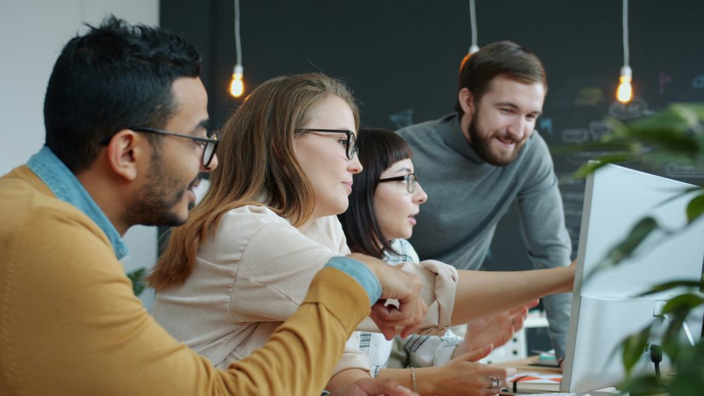 Équipe de professionnels collaborant autour d'un écran d'ordinateur lors d'une session de formation